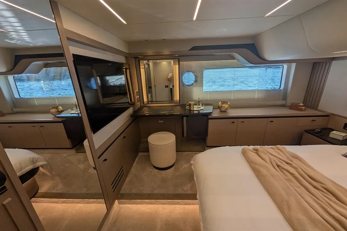 Luxury yacht interior featuring a bedroom with a TV, decorative items, and natural light from window blinds.